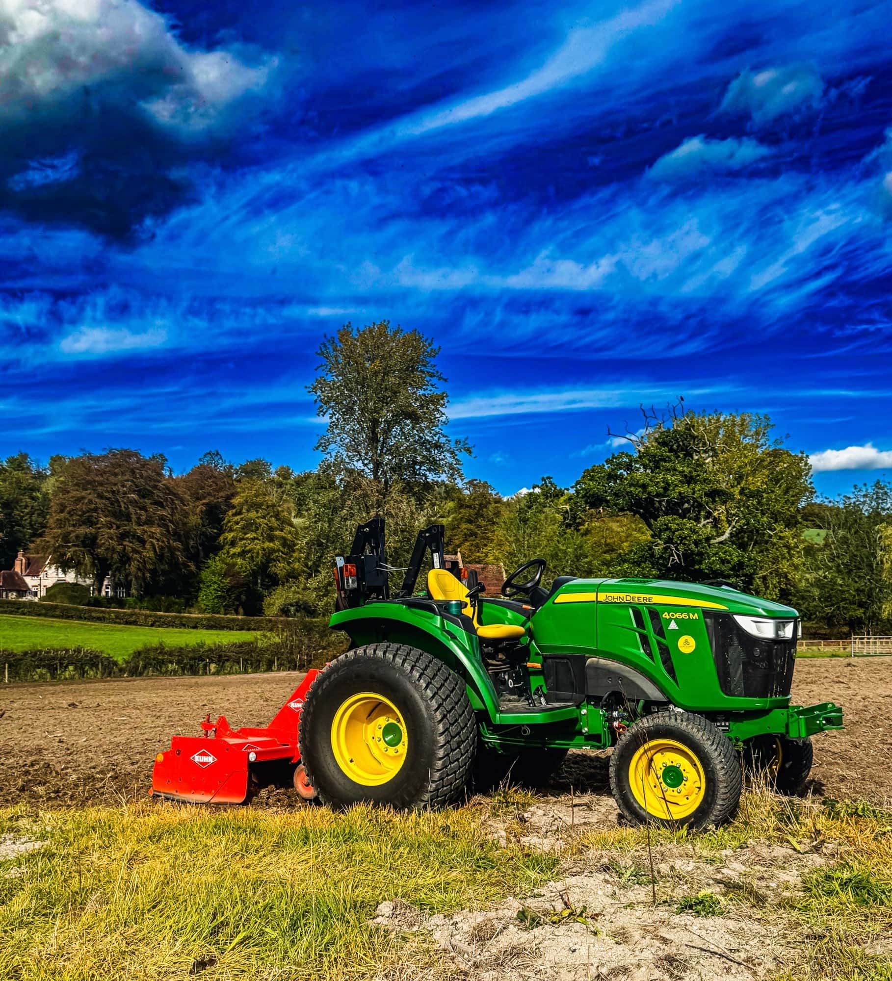 John Deere 4066M compact tractor with a Kuhn rotavator working the cleared East Meon paddock, with the valley and treeline behind
